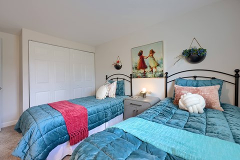 A bedroom with two beds and a painting on the wall.