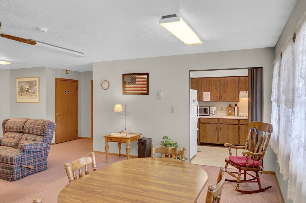 a living room with a wooden table and chairs and a kitchen in the background