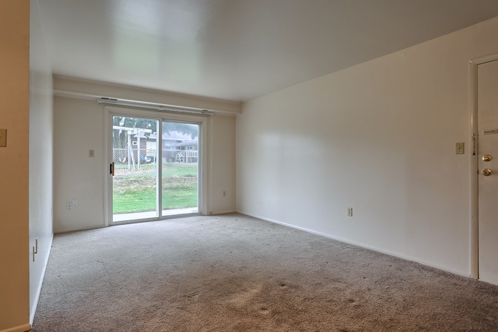 a living room with white walls and a sliding glass door