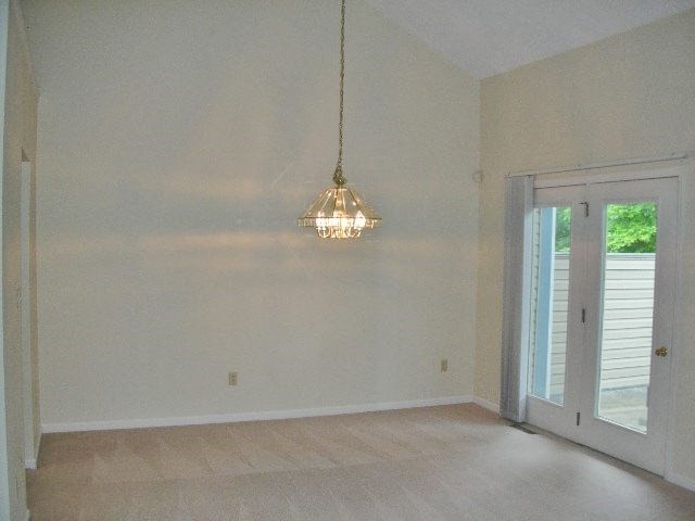 an empty living room with a chandelier and a door