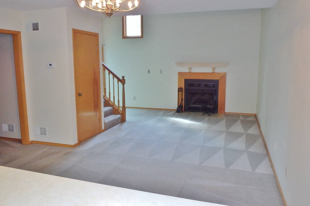 an empty living room with a tile floor and a fireplace