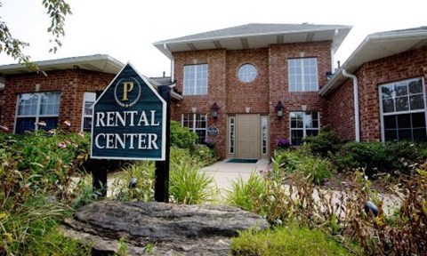 A rental center sign is in front of a brick building.