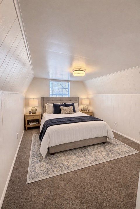 A bedroom with a bed, two nightstands, and a rug.