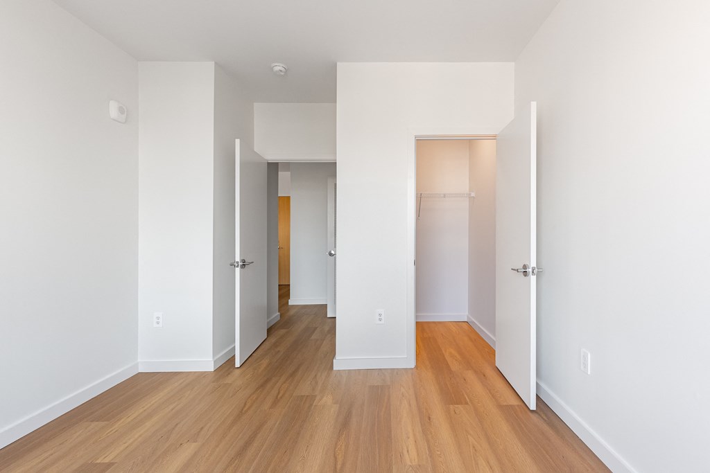 A long hallway with white walls and wood floors.