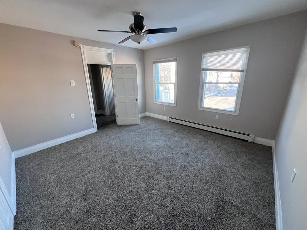 A room with a ceiling fan and two windows.