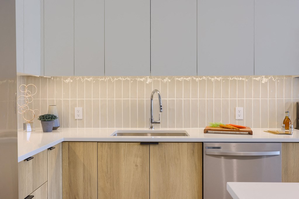 A kitchen with a white countertop and wooden cabinets.