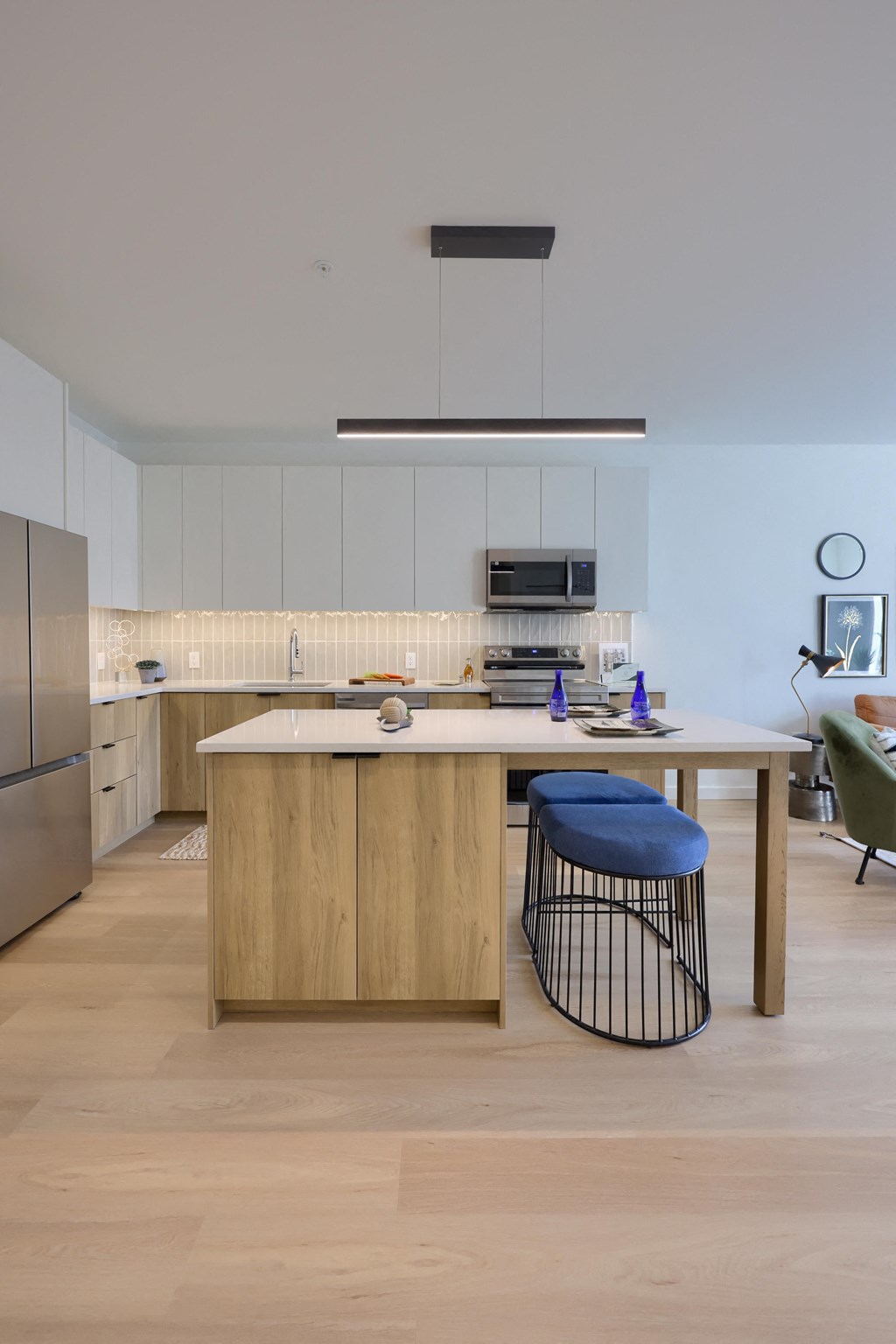 A kitchen with a white counter and a blue stool.
