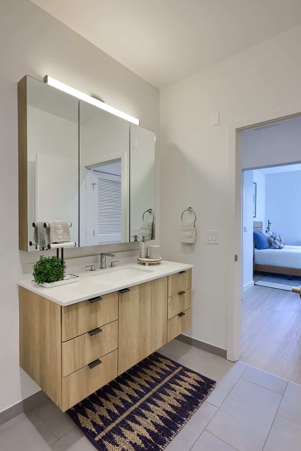 A bathroom with a sink, mirror, and rug.
