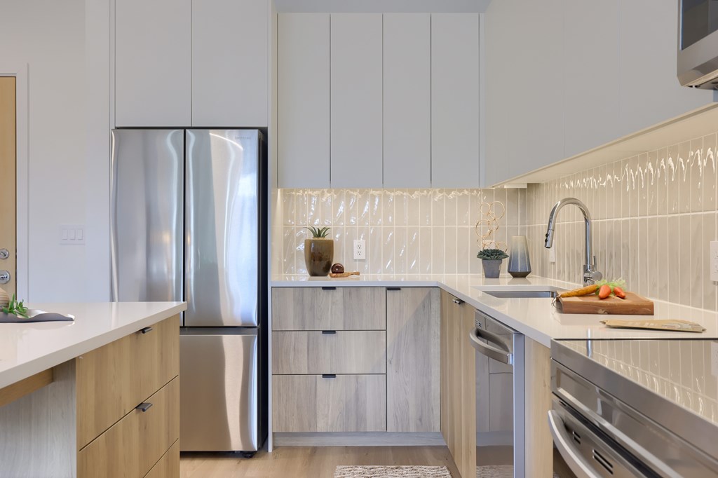 A modern kitchen with a stainless steel refrigerator and wooden cabinets.