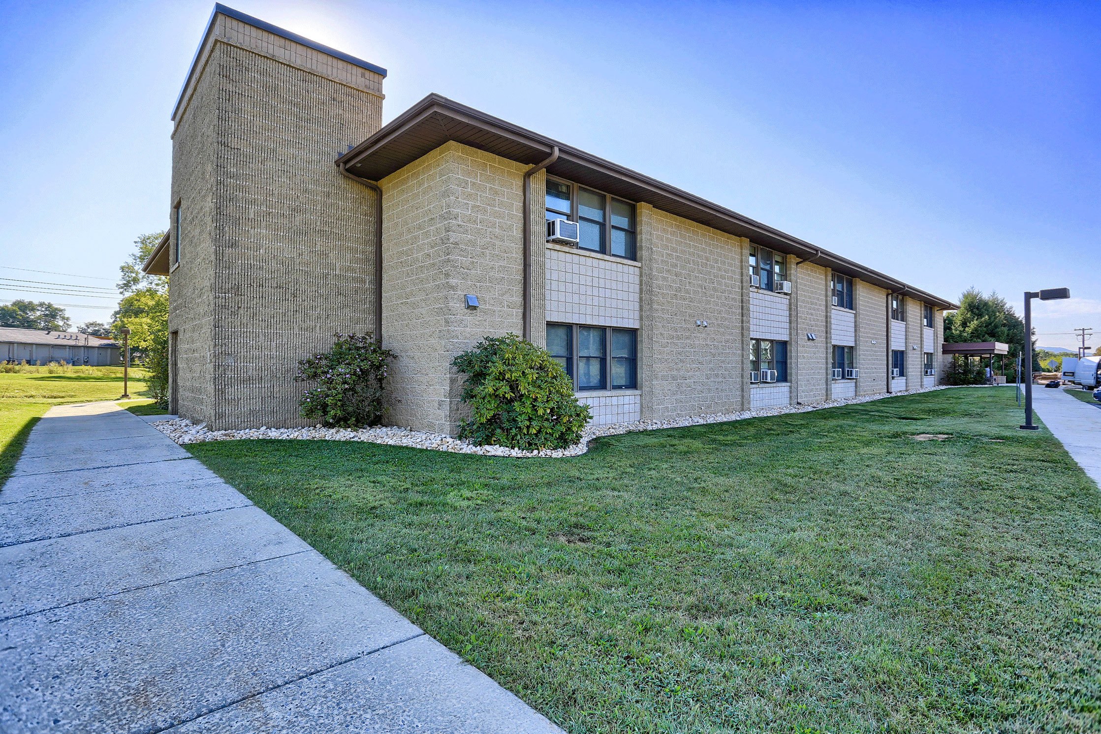 a brick building with green grass and a sidewalk
