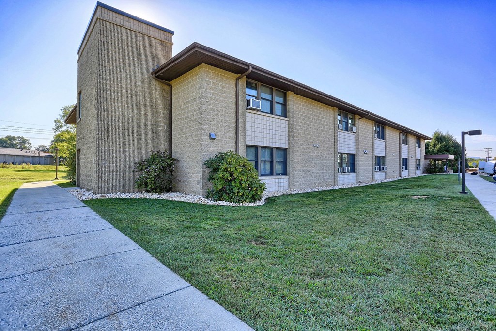 a brick building with green grass and a sidewalk
