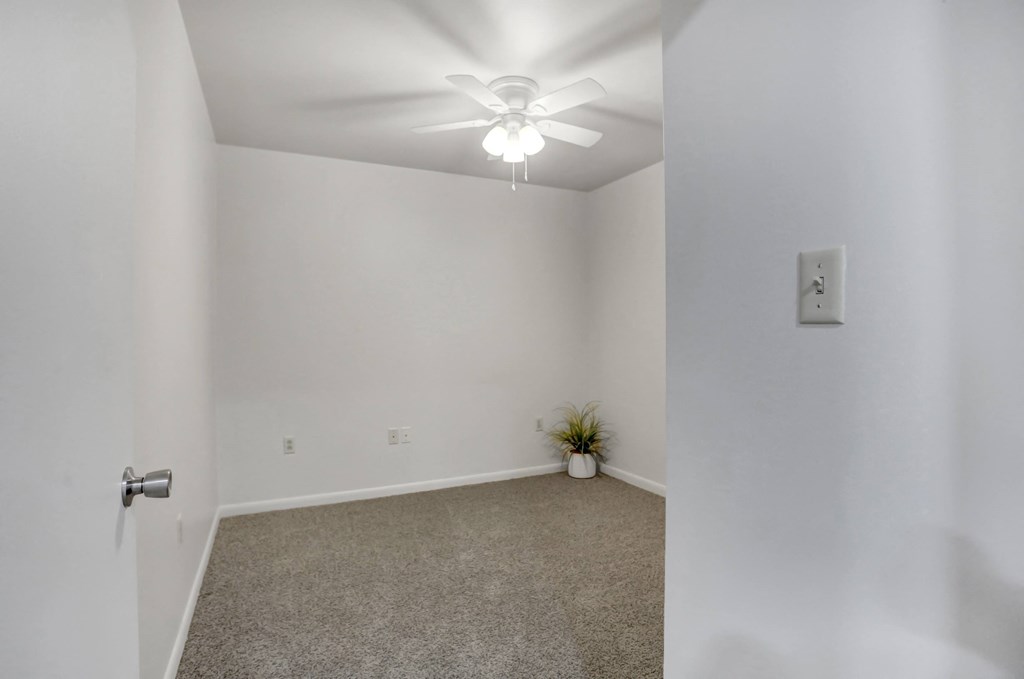 an empty room with white walls and a ceiling fan