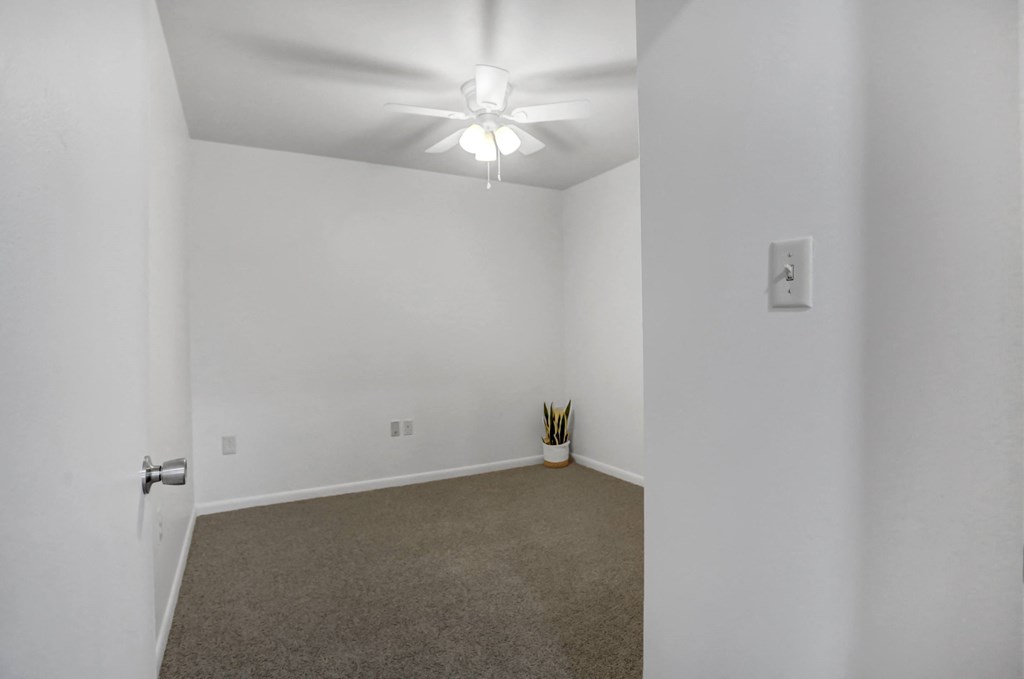 an empty living room with white walls and a ceiling fan