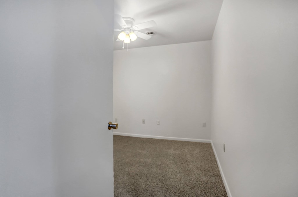 an empty room with white walls and a ceiling fan