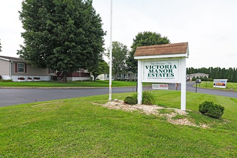 A sign for Victoria Manor Estates stands in a grassy area.