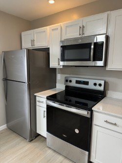 A kitchen with a stainless steel refrigerator, microwave, oven, and cabinets.