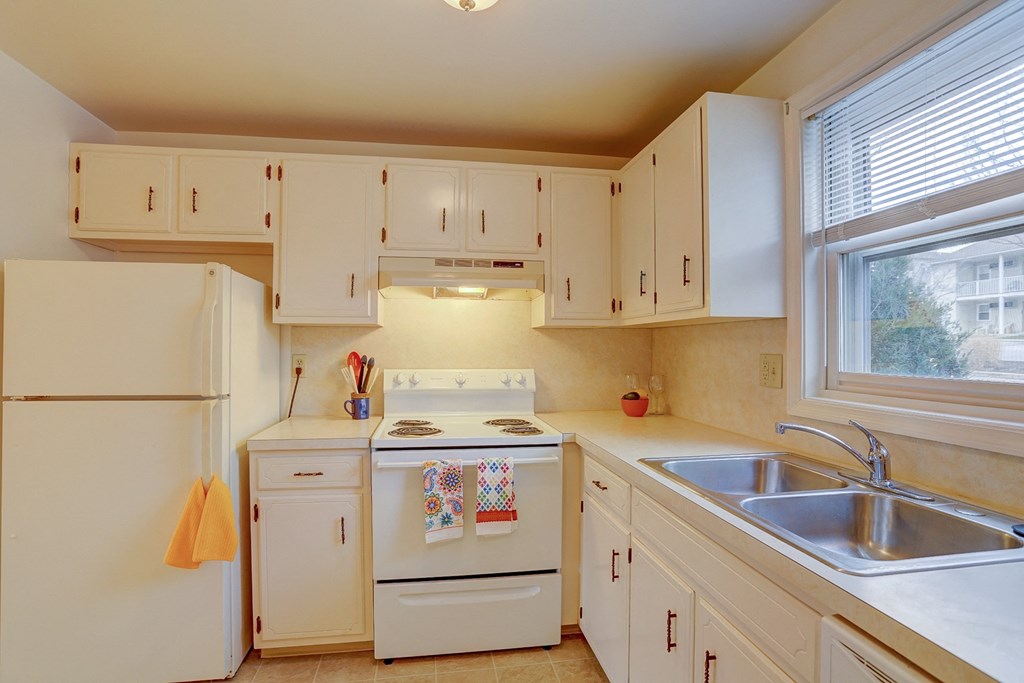 a kitchen with white appliances and white cabinets and a sink
