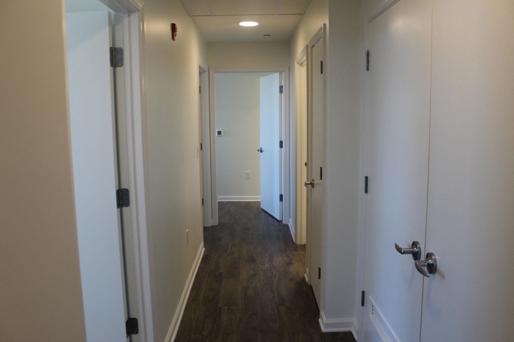 a hallway with wood floors and white walls and a door