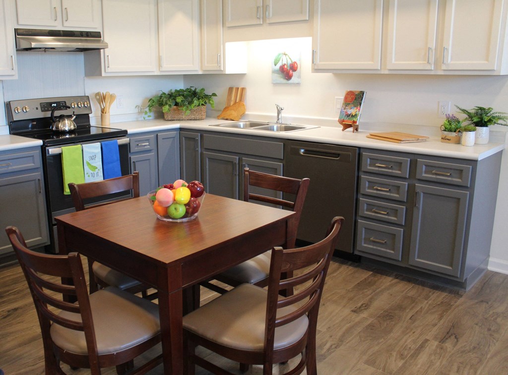 a kitchen with gray cabinets and a table with a bowl of fruit