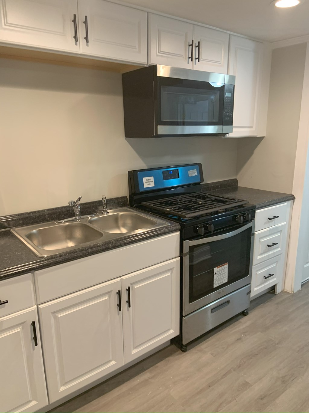 A modern kitchen with a black stove top oven and a black microwave above it.