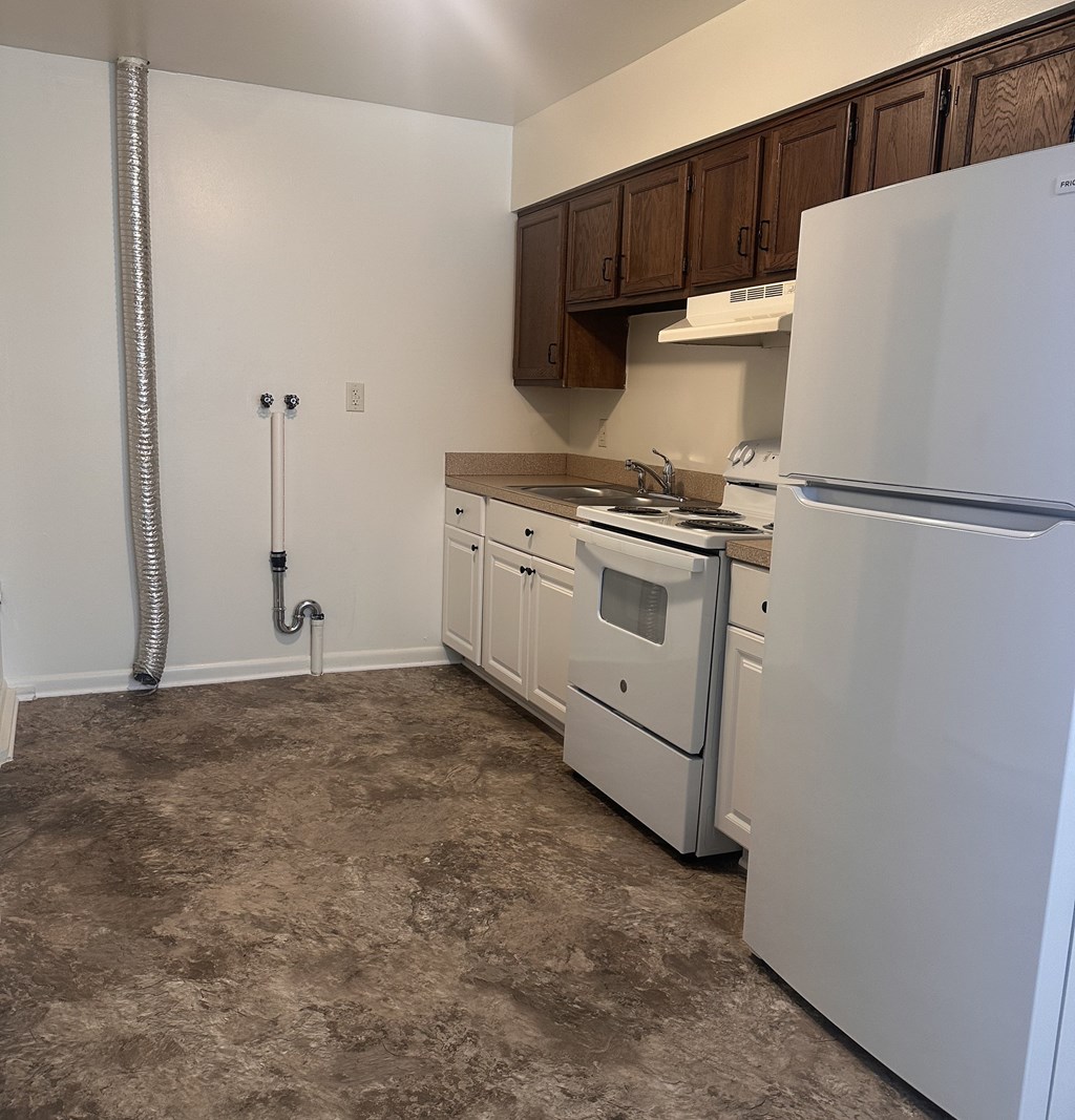A kitchen with a white refrigerator, white stove, and white oven.