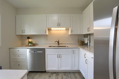 A kitchen with white cabinets and a stainless steel refrigerator.