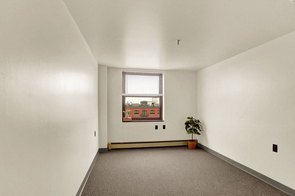 a bedroom with white walls and a large window