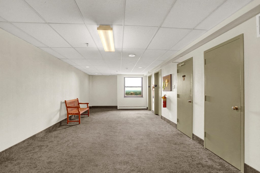 a long corridor with white walls and gray carpet