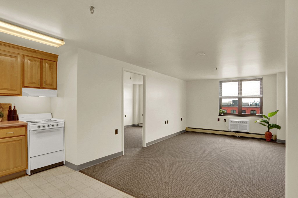a kitchen and living room with white walls and gray carpet