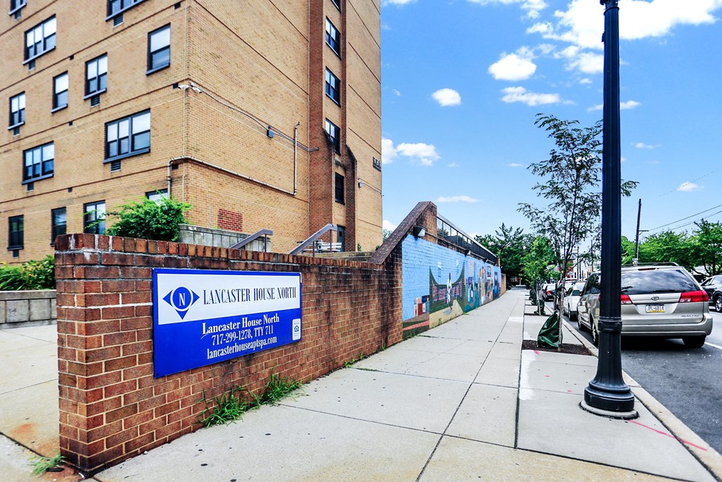 a brick wall with a blue sign and a brick building in the background