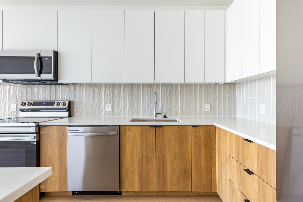 A kitchen with a stainless steel dishwasher and wooden cabinets.
