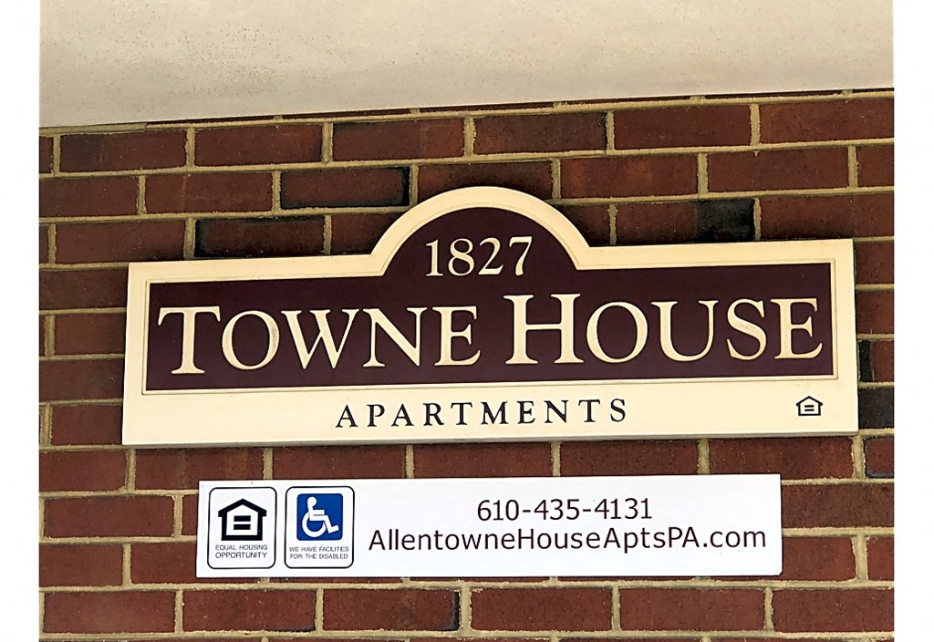 a sign for a town house apartments on a brick wall