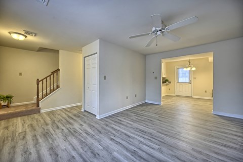 an empty living room with a ceiling fan and a staircase