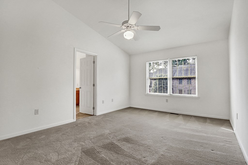 an empty living room with a ceiling fan and a window