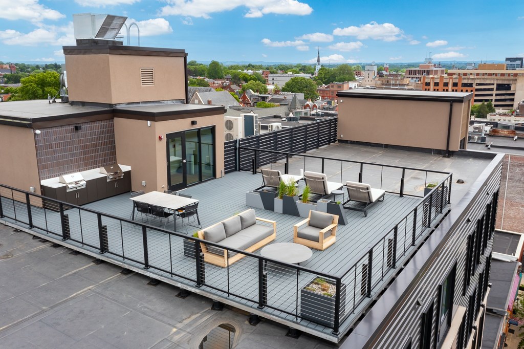A rooftop patio with a black railing and furniture.