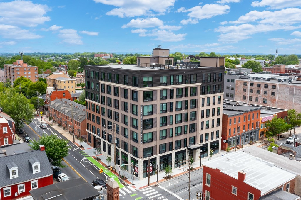 A large building with a green roof is in the middle of a city street.