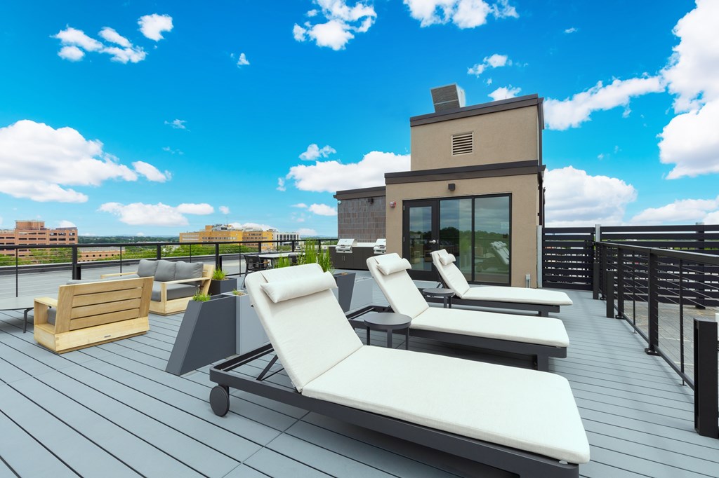 A sun lounger on a wooden deck overlooking a city.