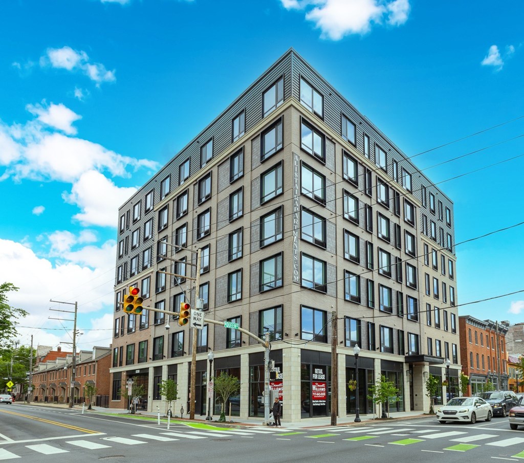 A large building with many windows is situated on a street corner.