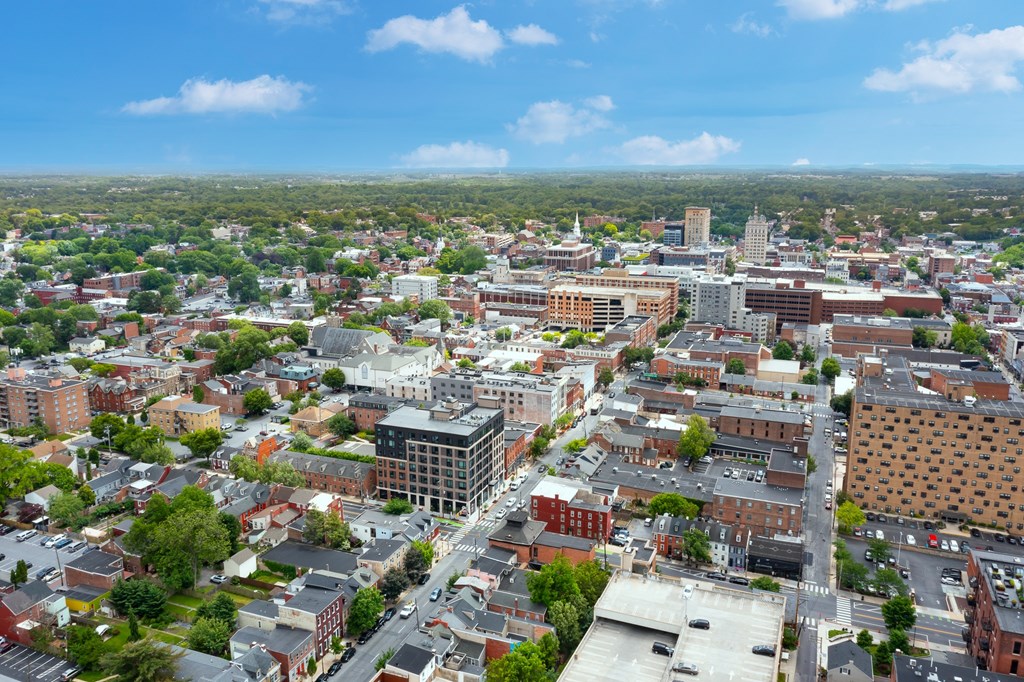 A cityscape with buildings of various sizes and shapes, surrounded by greenery.