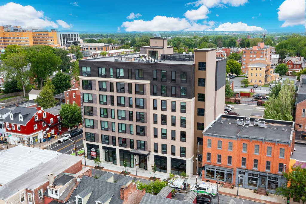 A modern building with a flat roof is surrounded by other buildings.