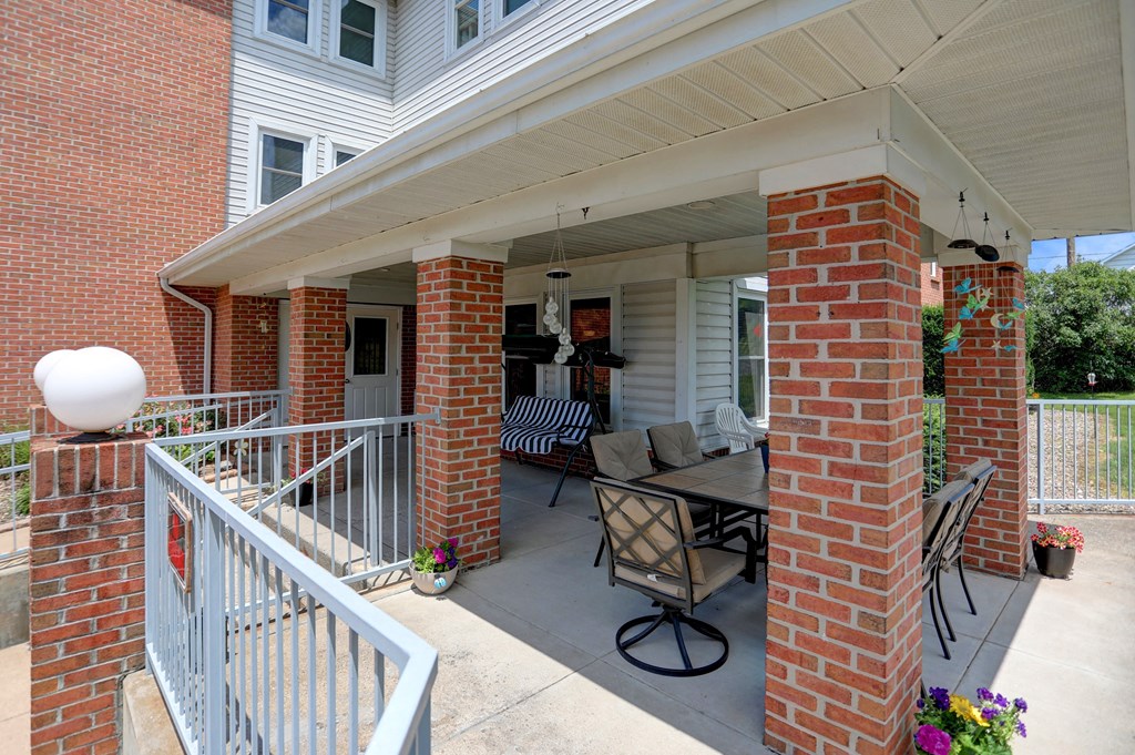 a patio with a table and chairs in front of a house