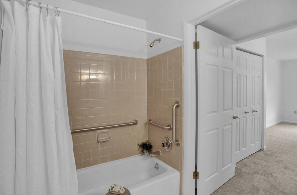 a bathroom with tan tiles and a white shower curtain