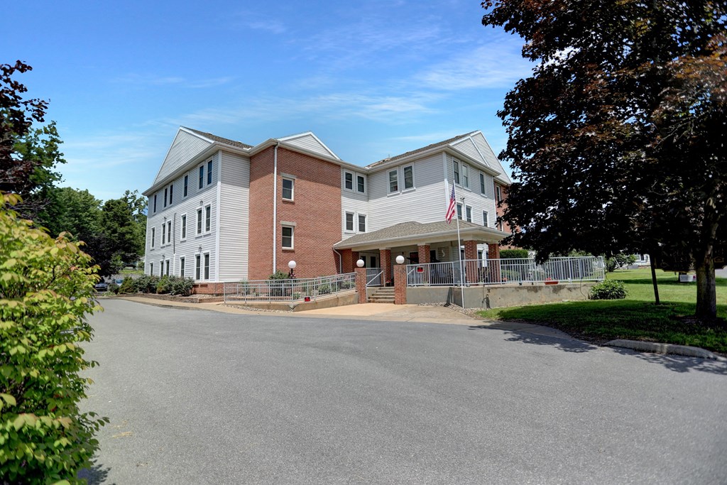 Apartments in Three Springs | Three Springs Estates | a large brick building with a gray roof and a black asphalt road in front of it