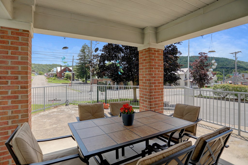 a patio with a wooden table and chairs with a potted plant on it