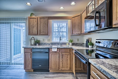 an updated kitchen with wood cabinets and black appliances