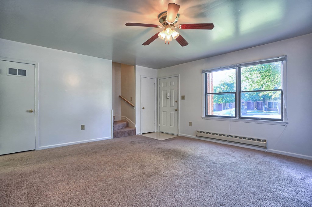 an empty living room with a ceiling fan and a large window