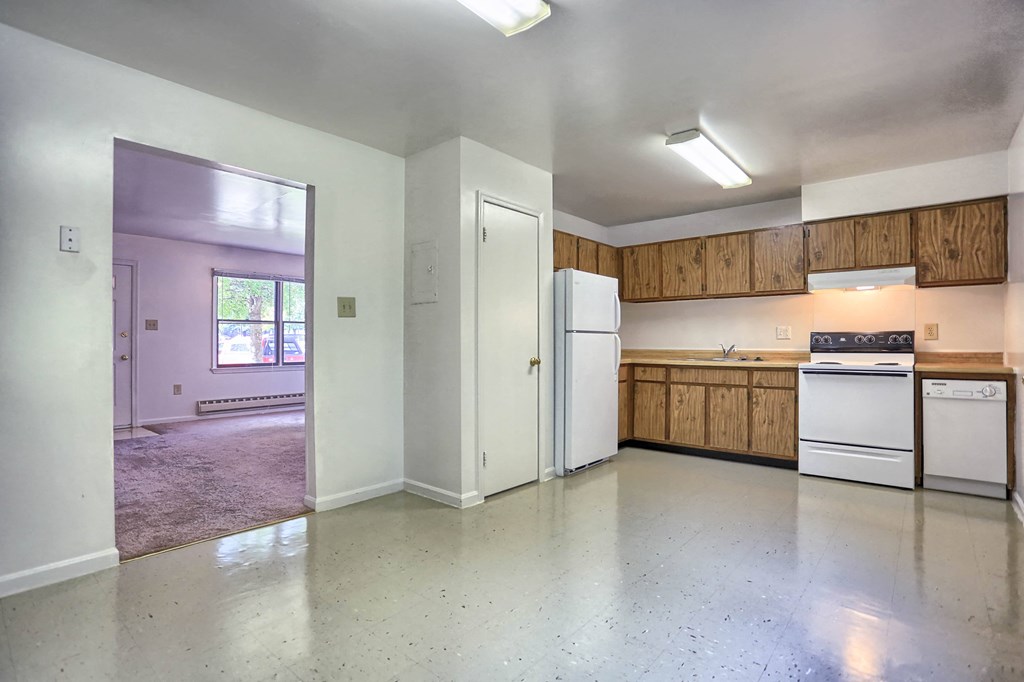 an empty kitchen with white appliances and wooden cabinets