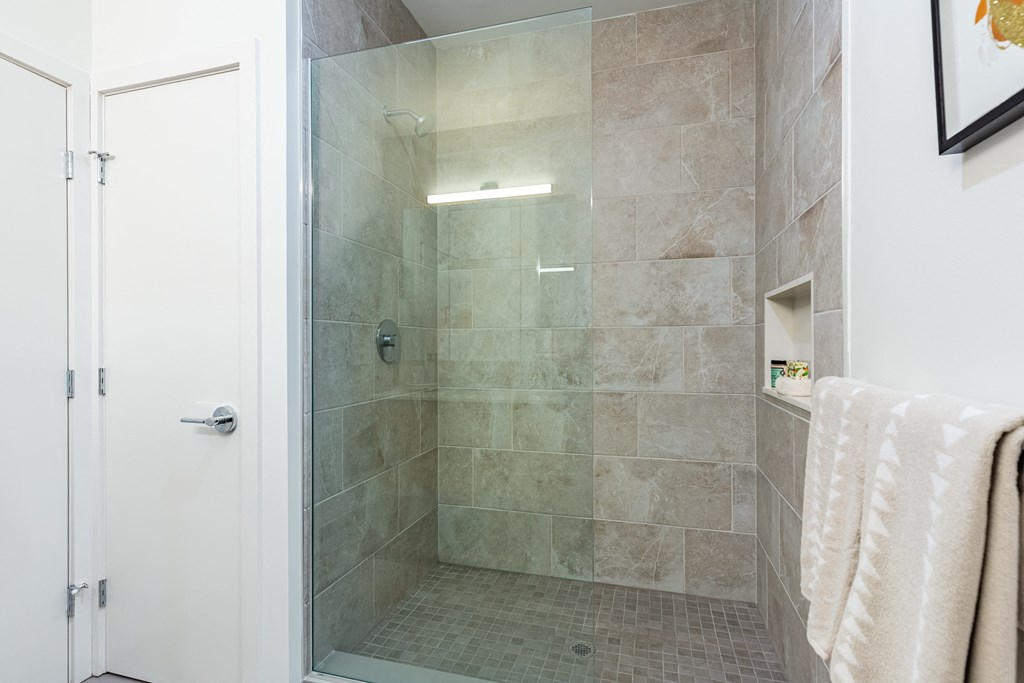 A bathroom with a glass shower door and a white door.