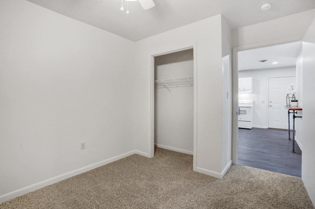 a bedroom with white walls and a closet with a mirrored door
