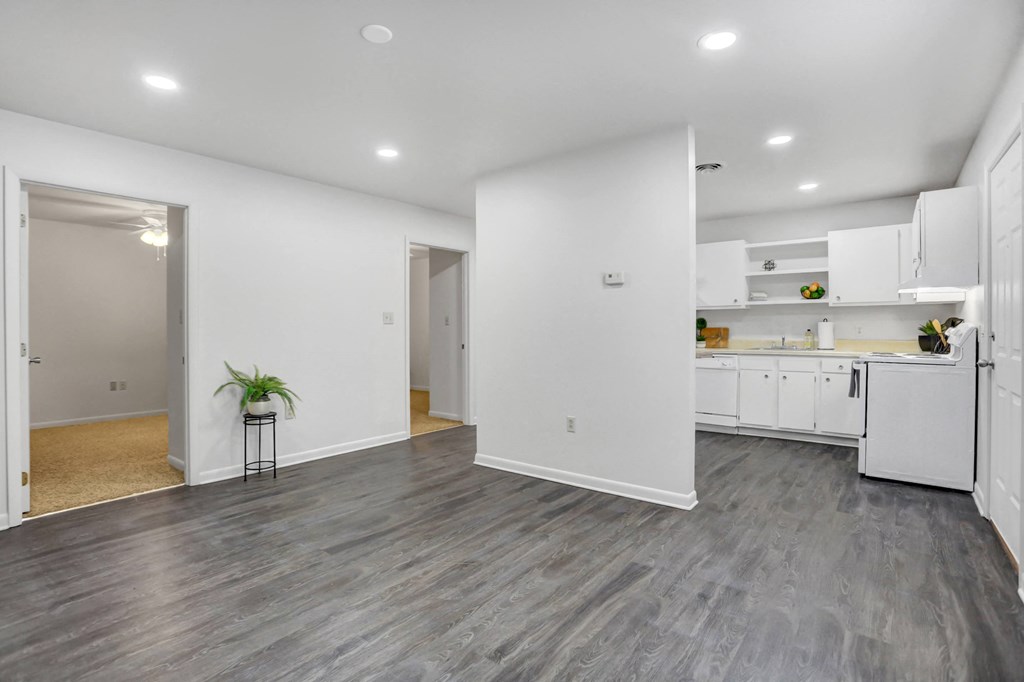 the living room and kitchen in a new home with white walls and wood flooring